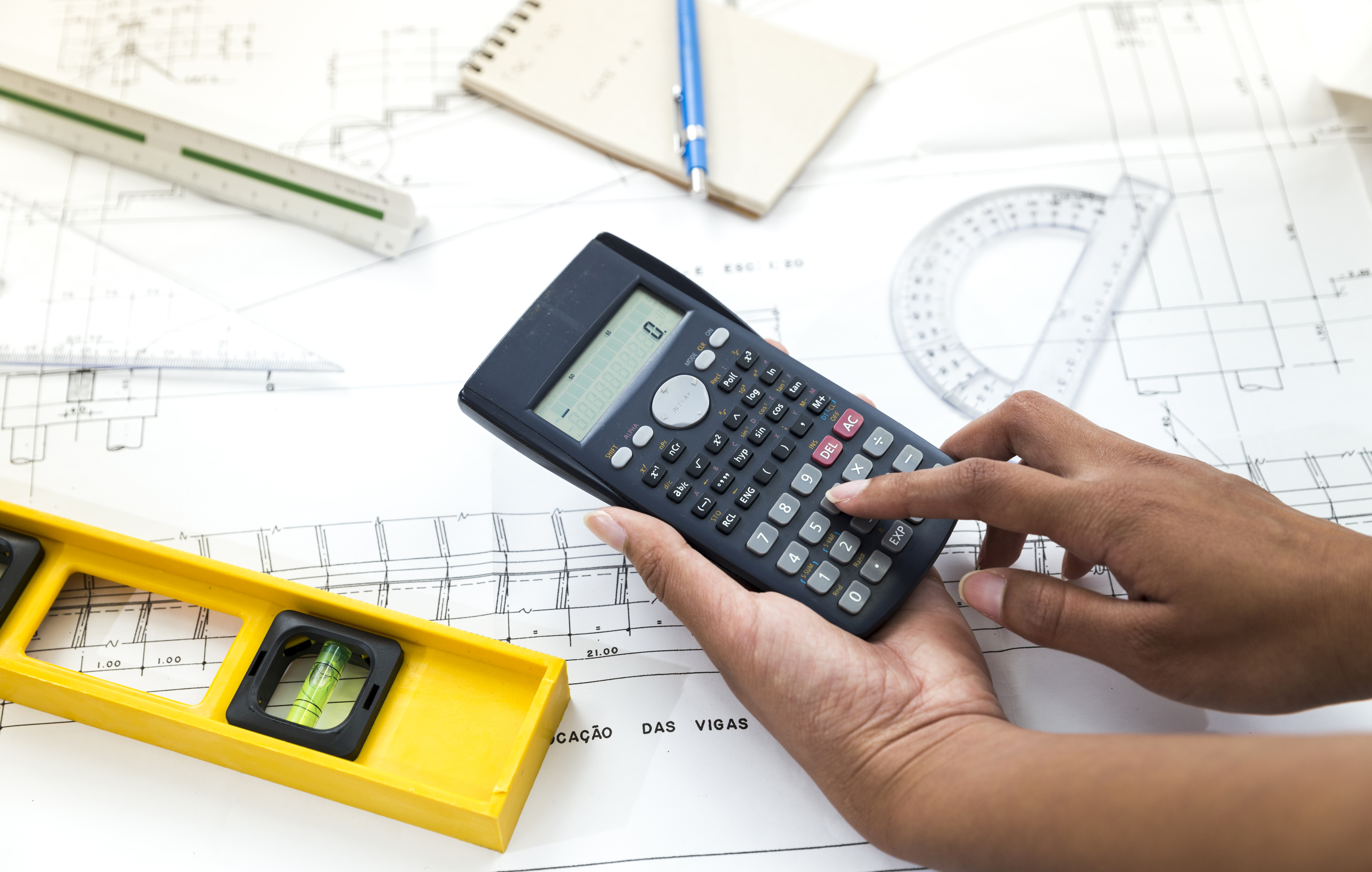 woman-using-calculator-near-plan-equipments